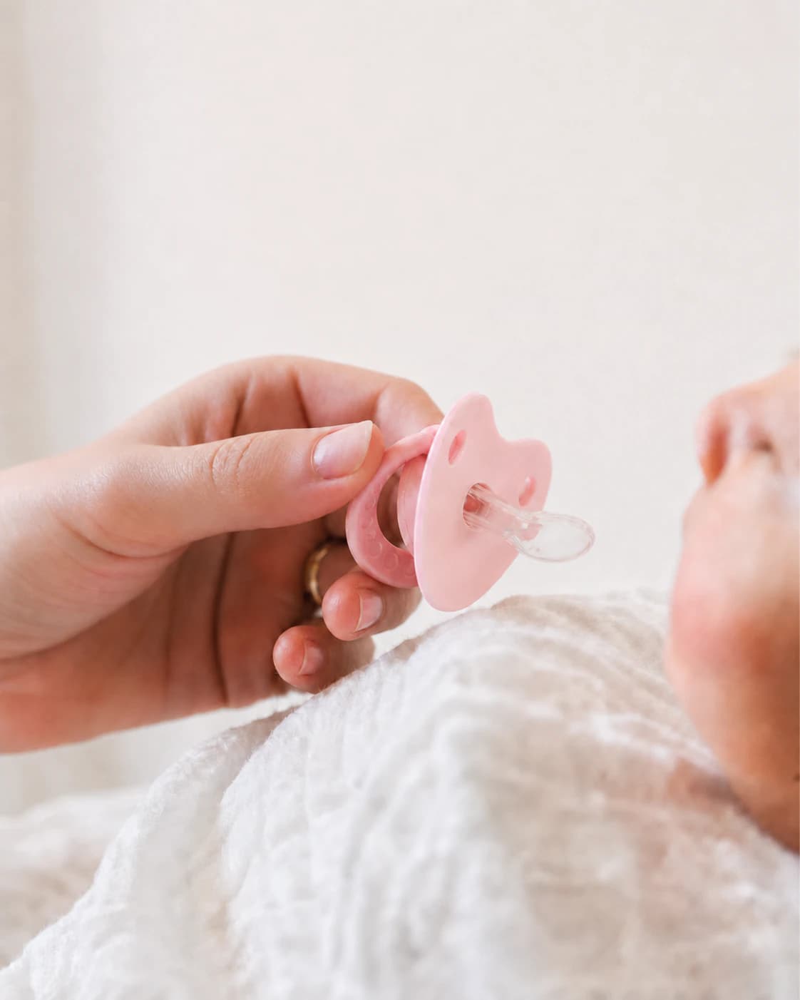 Close-up parent testing photo of a Baby Bee Blossom pink pacifier before settling