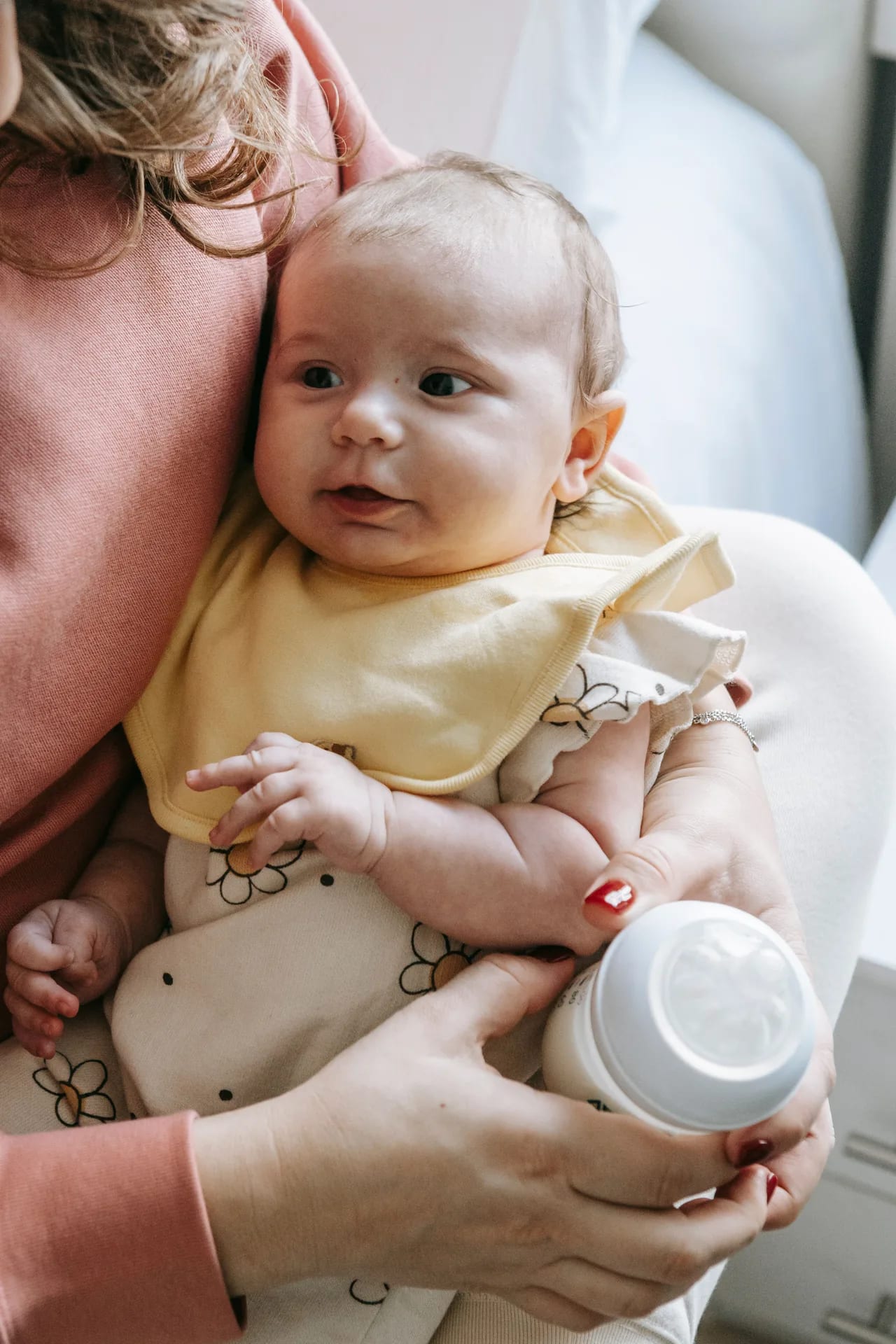 A parent holding a baby close during a bottle feed