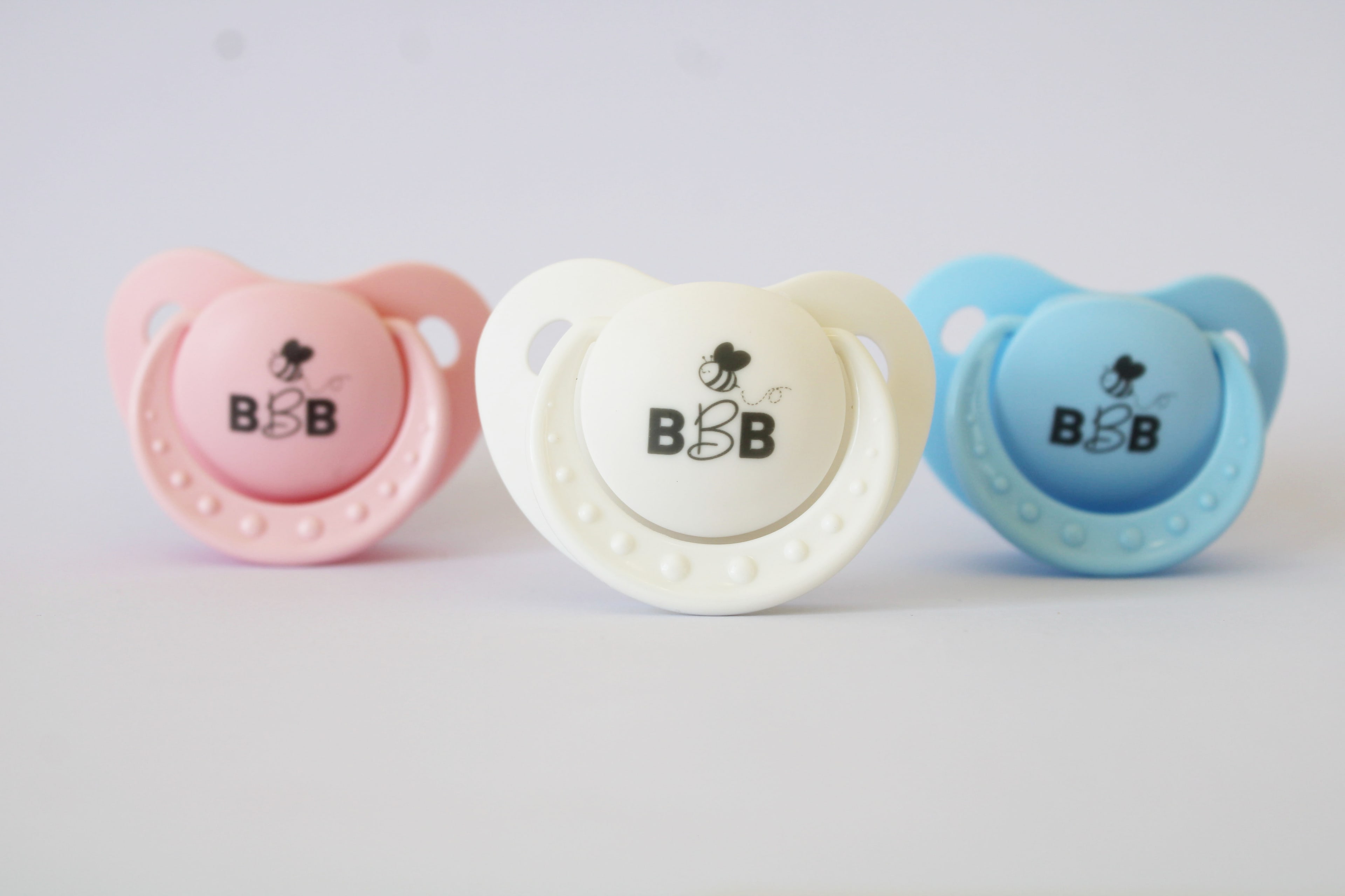 Pink, white and blue Baby Bee Blossom orthodontic baby pacifiers